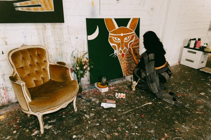 The studio: a velvet armchair, paint-spattered floor and Mugdha Martin at work on a canvas